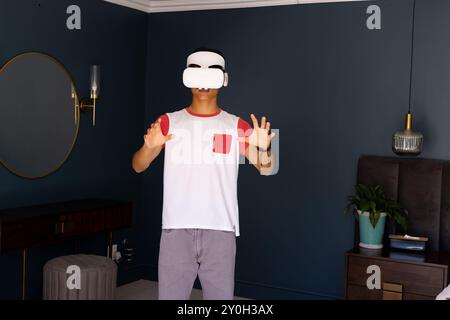 Using VR headset, asian man exploring virtual reality in modern living room Stock Photo