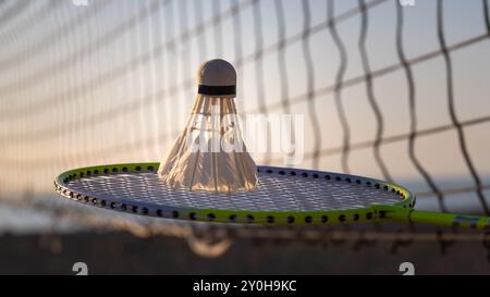Close-up of a badminton racket with a shuttlecock on the background of a net on a beach court, copy space. Badminton sports Stock Photo