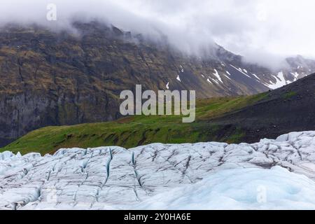 Mountain landscape with retreating Skaftafell Glacier in Vatnajokull National Park, Iceland. Blue glacier ice with green grasslands in the background. Stock Photo