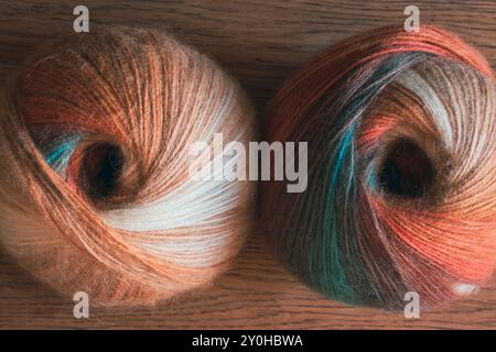 Two multi coloured yarn balls on table. Bright knitting yarn. Knitting hobby. Handicraft concept. Wool and alpaca wool threads. Autumn fashion Stock Photo