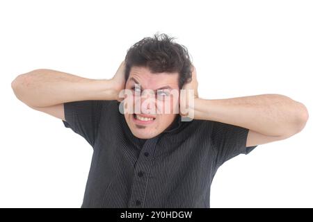 Frustrated and stressed young man  holding head in hands  while standing against white background Stock Photo