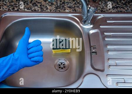Close-up of hand making okay sign after cleaning dirty sink in kitchen Stock Photo