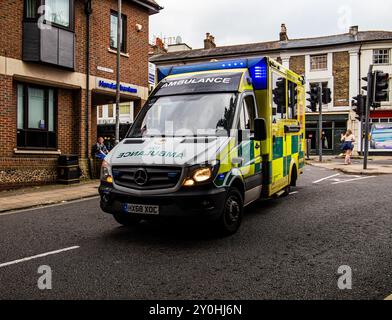 A yellow and green ambulance is driving down a city street, offering emergency medical services in an urban environment. Stock Photo