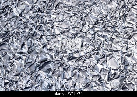 crumpled thin aluminum foil reflecting light, thin foil for use in cooking crumpled from different sides, there may be dust and crumbs from food on th Stock Photo