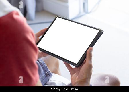 Holding tablet with blank screen, person sitting and browsing content, copy space Stock Photo