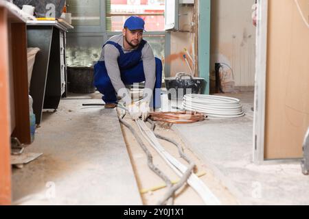 Man electrical installer laying cables through trench Stock Photo