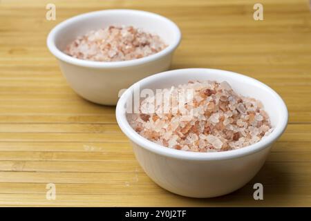 A close up studio photo of Coarse Himalayan pink sea salt in small white bowls Stock Photo