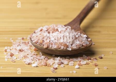 A close up photo of pink Himalayan sea salt on a wooden spoon and on a table Stock Photo