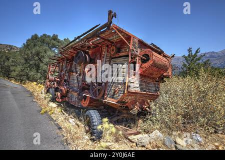 Dilapidated, rusted combine harvester next to the road under blue sky, wrecked vehicle, Crete, Greek Islands, Greece, Europe Stock Photo