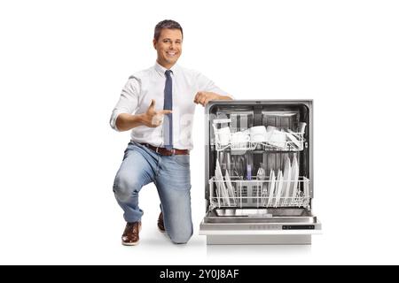 Businessman pointing at clean dishes inside a dishwasher isolated on white background Stock Photo
