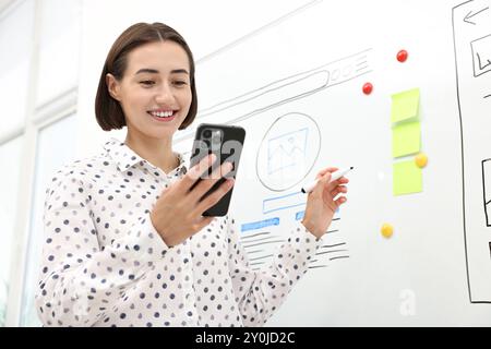 Developing UI design. Woman drawing website wireframe on whiteboard indoors Stock Photo