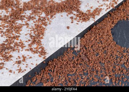 a large number of pieces and crumbs of chocolate scattered on the surface, using small pieces of chocolate in cooking Stock Photo