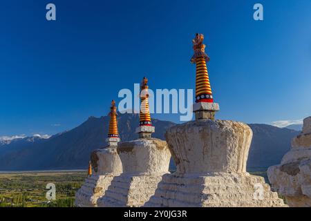Many white Stupas in a row on a mountain with blue sky in the background Stock Photo