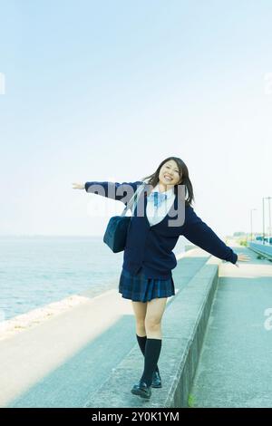 Japanese high school girl walking on a breakwater Stock Photo