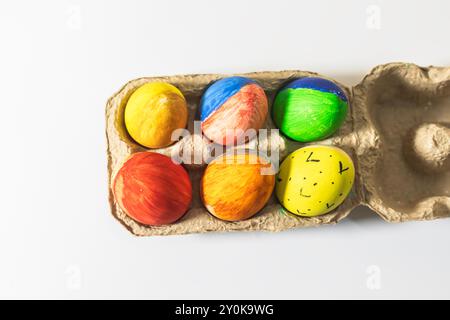 Colorful easter eggs in a cardboard box on a white background. Top view Stock Photo