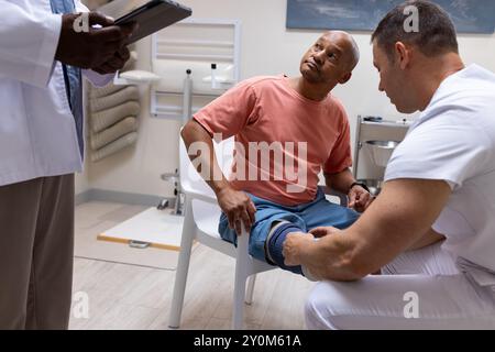 Doctor examining patient's leg while another doctor taking notes in prosthetic lab Stock Photo