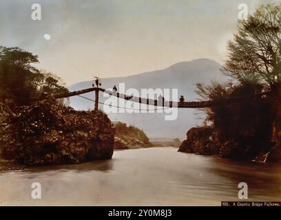 The bridge at Kamaguchi 1890 by  Kusakabe Kimbei ( The hanging bridge of Kamaguchi was long celebrated as a landmark of the Mount Fuji area. )   Japanese hand-coloured black and white photo Japan late 19th - beginning of 20th-century vintage albumen photograph ( Historic History ) digital improved reproduction. Stock Photo