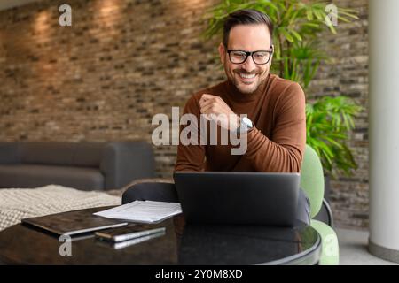 Portrait of handsome engineer working on project over laptop while sitting at table in modern office Stock Photo