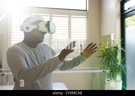 Using VR headset, man with prosthetic arm interacting in rehabilitation medical clinic, copy space Stock Photo