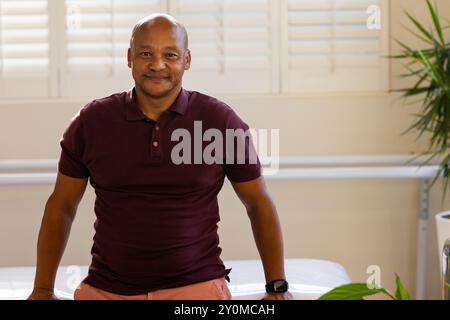 Smiling man in prosthetic medical clinic wearing smartwatch, leaning on table Stock Photo
