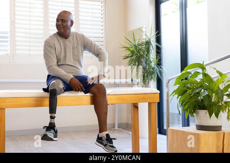 Sitting on bench, man with prosthetic leg smiling in rehabilitation center Stock Photo