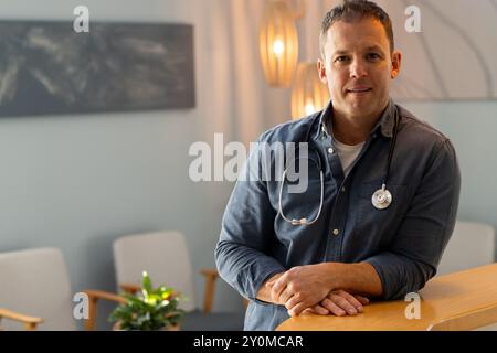 Smiling confidently, doctor with stethoscope standing in medical office, copy space Stock Photo