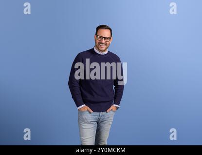Portrait of laughing businessman with hands in pockets standing isolated over blue background Stock Photo