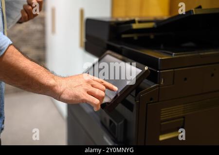 Cropped hand of businessman operating modern computer printer for photocopying documents in office Stock Photo