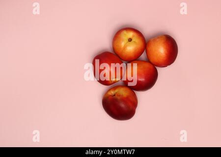 Ripe nectarines on a pink background with copy space. Flat lay, top view of fresh fruit on a table. Healthy eating concept. Stock Photo