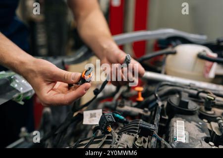 Closeup hands of experienced car electrician mechanic male working with electric block in car, servicing engine in automobile repair and renew service Stock Photo