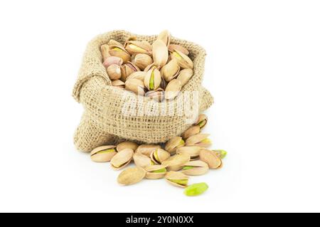 Peeled roasted pistachios in burlap sack isolated on white background, healthy nut Stock Photo
