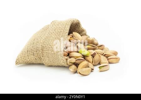 Peeled roasted pistachios in burlap sack isolated on white background, healthy nut Stock Photo