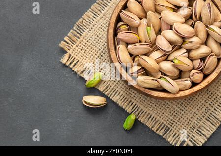 Roasted pistachios in bowl on gray rustic wooden table, healthy nut Stock Photo