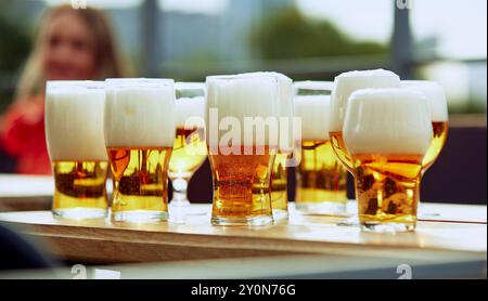 Beer mugs stands on wooden table during summer barbecue party outdoors. Friends preparing food, chatting and having drinks together Stock Photo