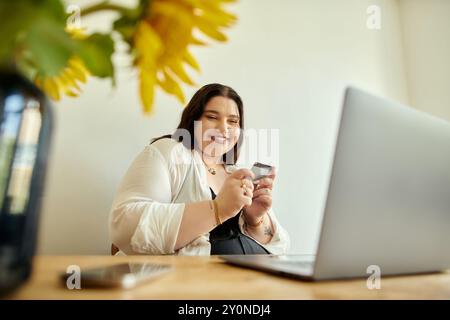 A joyful woman smiles while holding her phone at a cozy home setting. Stock Photo