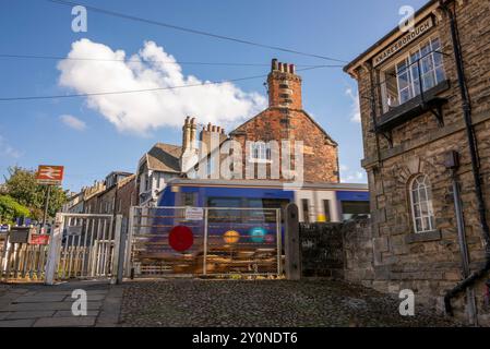 Train passing through Knaresborough Railway Station, Knaresborough, North Yorkshire, UK with signal box and crossing. Stock Photo