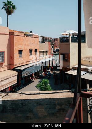 A lively market scene in Marrakech captures the essence of local life, with colorful buildings lining the streets, vendors selling goods, and people e Stock Photo