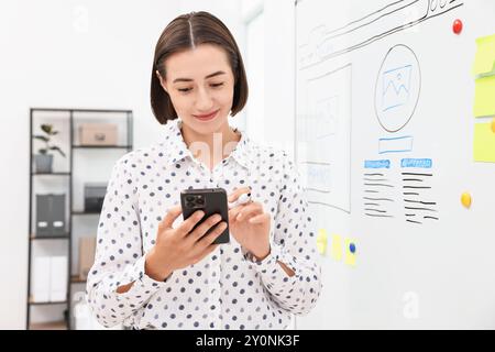 Developing UI design. Woman drawing website wireframe on whiteboard indoors Stock Photo