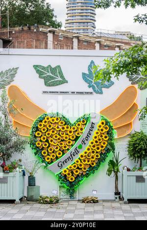 London, UK. 3rd Sep, 2024. Life goes on around the memorial wall (which includes a winged heart made up of messages on sunflowers), as the tower looms above, on the day before the report on the Grenfell Tower disaster is released. Those involved remain upset and frustrated that no-one has been called to account for the tragedy and hope this may change after tomorrow. Credit: Guy Bell/Ģ����ý Live News Stock Photo