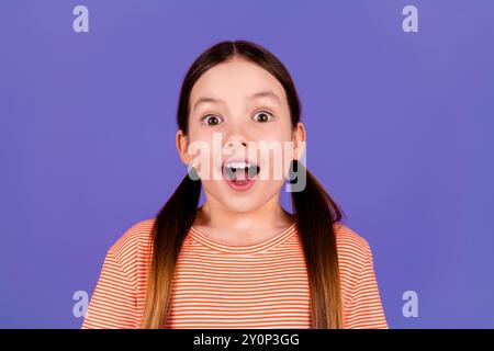 Photo portrait of cute little girl shocked impressed reaction dressed stylish red clothes isolated on violet color background Stock Photo