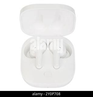 Top view of white wireless earbuds seated in an open charging dock, captured on a white background. Stock Photo