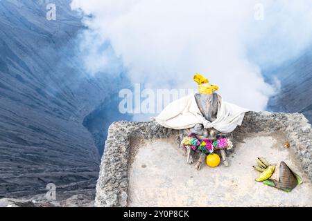 Stone statue of ganesha with offerings overlooking the smoking crater of mount bromo volcano in java, indonesia Stock Photo