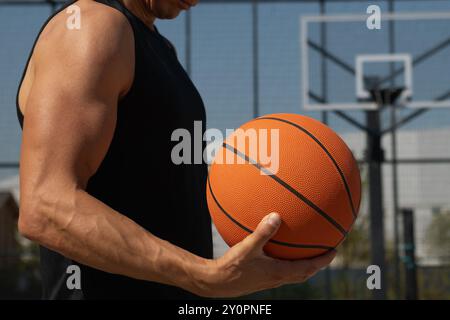 Basketball orange ball in mans hand on sport court. Sport background. Team sport. Close up. Copy space. Stock Photo