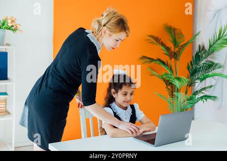 Teacher and girl studying at a desk with a laptop Stock Photo