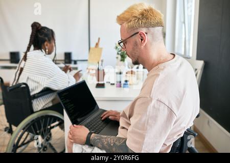 Team of coworkers collaborating in modern inclusive office utilizing laptops and technology Wheelchair users engaging in productive tasks wearing casual attire Stock Photo
