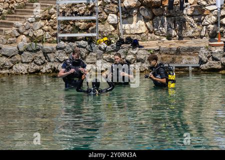 august 25, 2024, Ohrid Bay of the bones, North Macedonia divers in black scuba diving suits, man and a woman with oxygen bottles sink under the transp Stock Photo