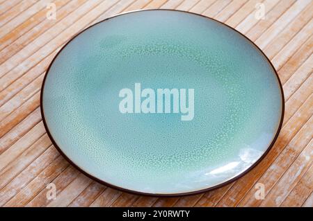 Blue ceramic plate with black edging on wooden background Stock Photo