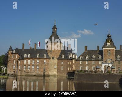 Historic castle with towers and flags reflected in the water under a clear blue sky, Anholt, North Rhine-Westphalia, Germany, Europe Stock Photo