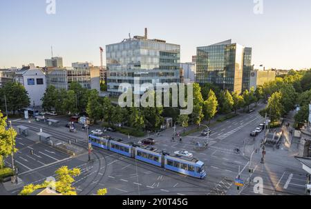 View from above of the crossroads at Stiglmaierplatz with tram, modern office buildings in the evening light, Loewenbraeu brewery building, Stiglmaier Stock Photo