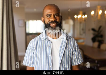 Smiling african american senior man in casual shirt standing in home, looking confident Stock Photo